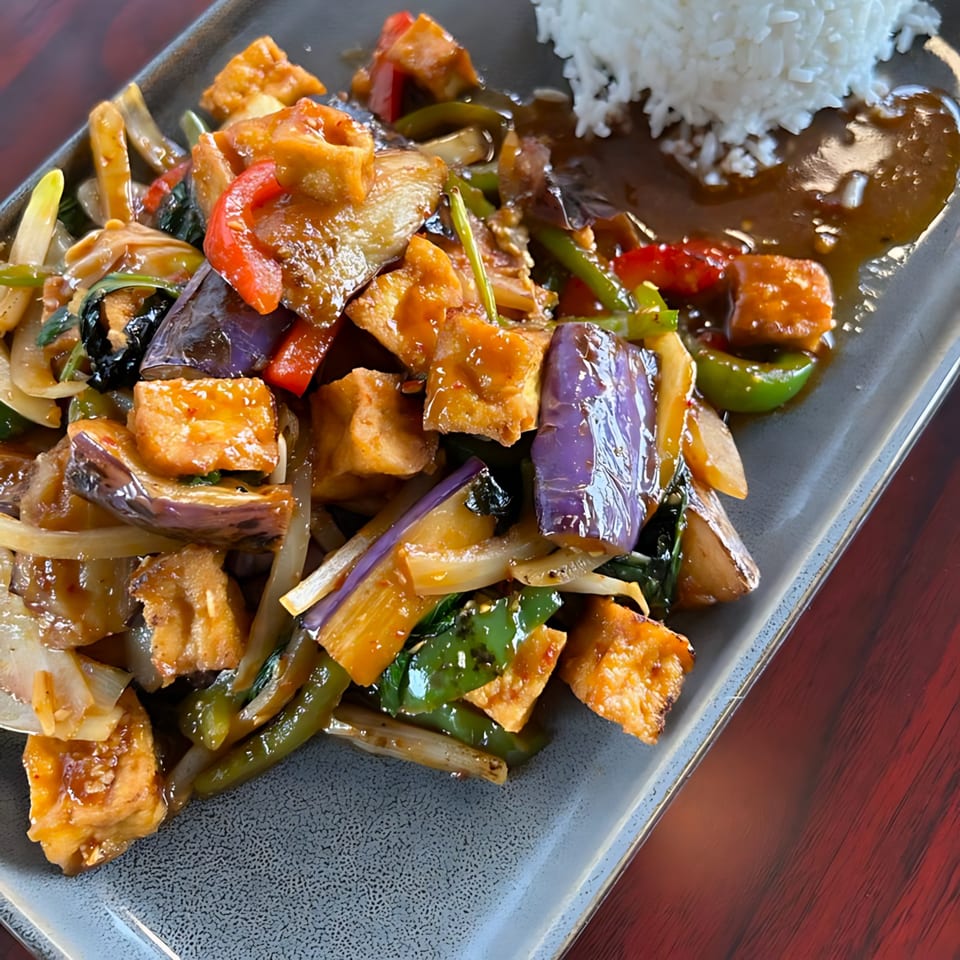 Monkey Thai Diner's stir-fried tofu, eggplant, and vegetables with rice on a rectangular plate.